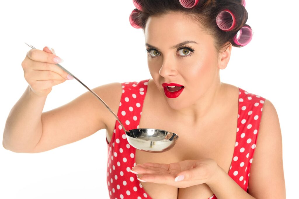 close-up portrait of emotional plus size housewife cooking with ladle isolated on white