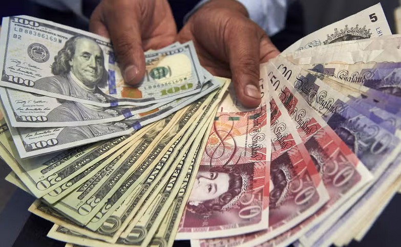 Hands holding spread-out banknotes in different currencies, including US dollars and British pounds, creating a visual akin to a small TV screen displaying wealth or vice versa.