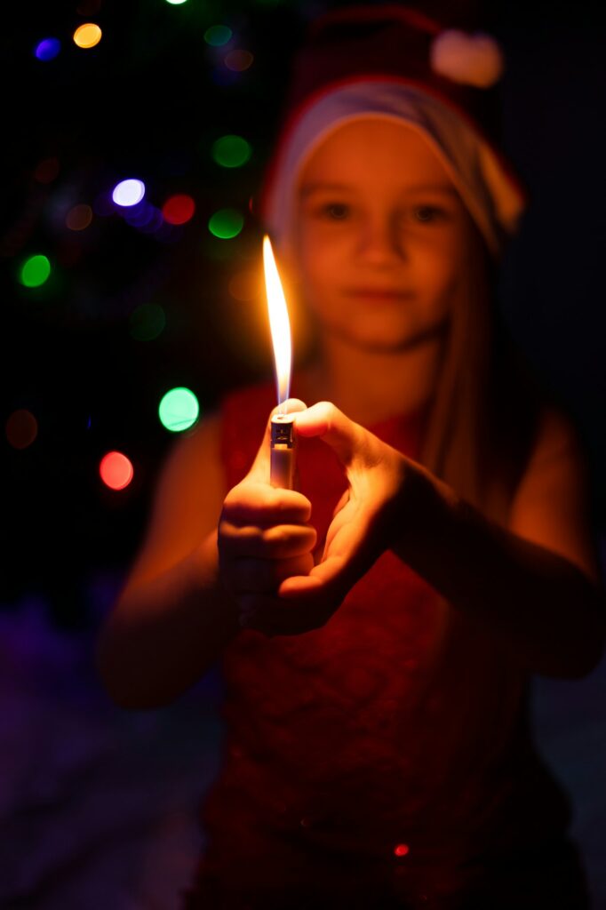 The child is holding a lighter in his hands, which burns like a candle.