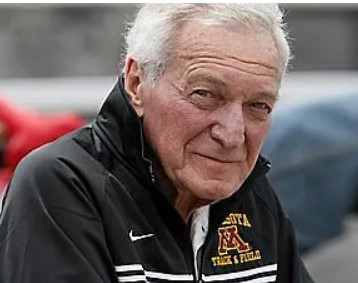 Elderly man, a true legend, wearing a University of Minnesota track and field jacket, looking at the camera with Gopher pride.