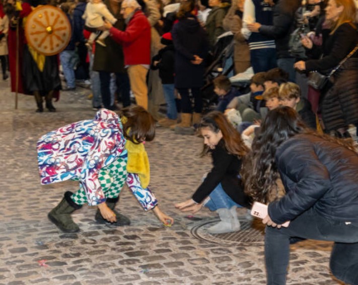 People crouching on a cobblestone street during the bustling outdoor event in Alcoy, where everything started to come alive.