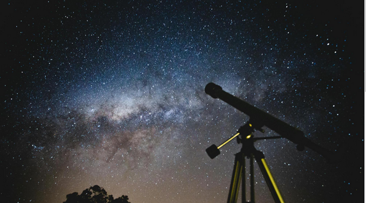Silhouette of a telescope pointed at a star-filled night sky with a visible Milky Way.