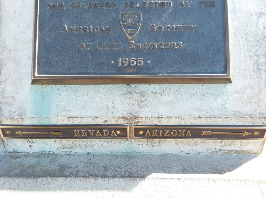 Bronze markers showing the state border between Nevada and Arizona rest beneath a 1955 plaque from the American Society of Civil Engineers, marking your step "Into the Belly of the Beast.
