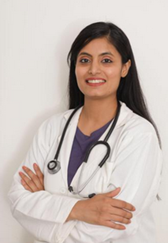 A woman wearing a white lab coat and stethoscope stands with arms crossed, smiling warmly as if ready to offer a reassuring hug, in front of a plain background.